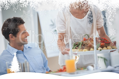 Smiling woman presenting a roast chicken during a dinner