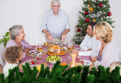 Composite image of grandfather carving the turkey