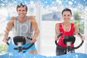 Smiling young couple working out at spinning class