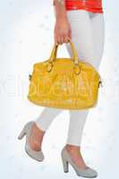 Composite image of woman in high heels walking with yellow bag