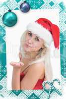 Composite image of woman wearing santa hat as she blows kiss