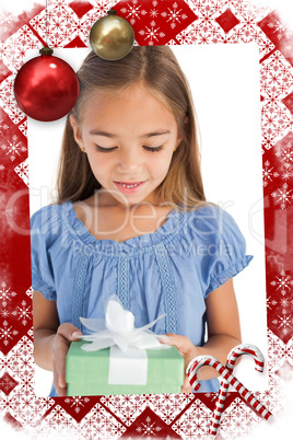 Composite image of cute little girl holding a wrapped gift