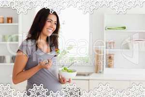 Beautiful pregnant woman holding a bowl of salad while standing