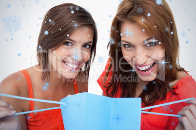 Two teenage girls holding a purchase bag while smiling