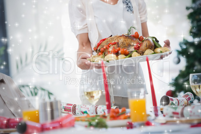 Composite image of woman bringing roast chicken at table
