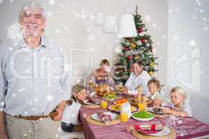 Composite image of smiling grandfather standing at the dinner ta