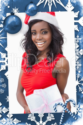 Composite image of woman standing holding a gift while smiling