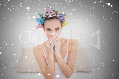 Cute natural brown haired woman in hair curlers sneezing in a ti