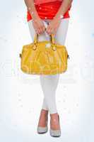 Composite image of woman in high heels holding yellow bag