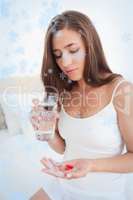 Woman looking down at the two pills she is going to take with water