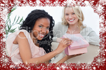 Woman holding a pink box smiles at the camera with her friend