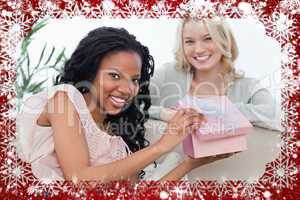 Woman holding a pink box smiles at the camera with her friend