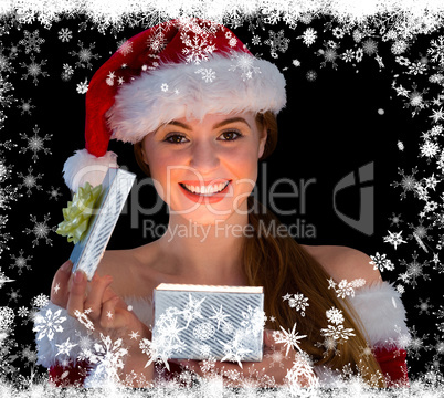 Pretty redhead in santa outfit opening a gift smiling at camera