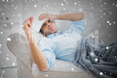 Composite image of sick man lying on sofa checking his temperatu