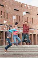 Happy students jumping in the air holding exam
