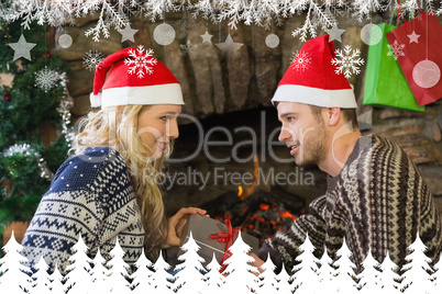 Man gifting woman in front of lit fireplace during christmas