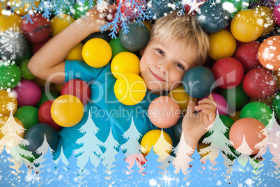 Composite image of happy boy playing in ball pool