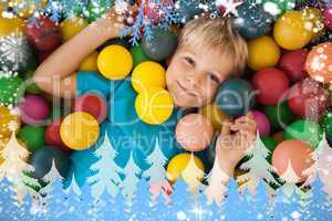 Composite image of happy boy playing in ball pool