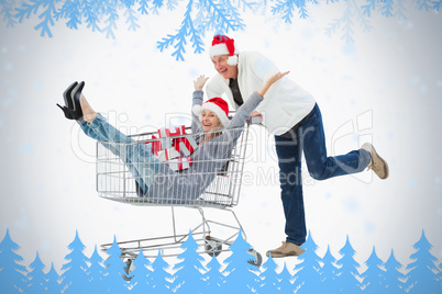 Festive mature couple in winter clothes with trolley and gifts