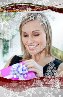 Happy woman opening a gift sitting on a sofa