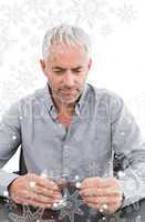 Serious mature man holding glass of water and pill at the table