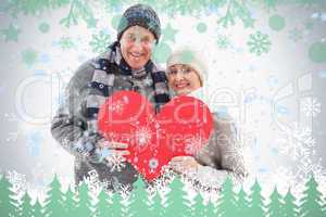 Happy mature couple in winter clothes holding red heart