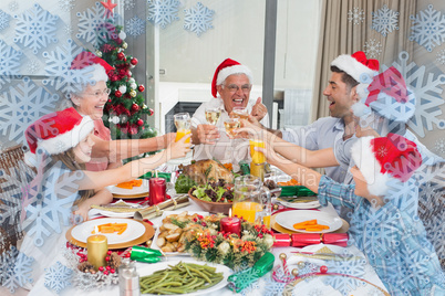 Family in santas hats toasting wine glasses at dining table