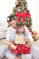 Composite image of surprised little girl opening presents with h