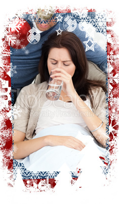 Composite image of sick woman drinking water lying on the sofa