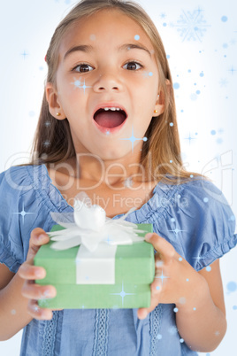 Composite image of excited little girl holding a wrapped gift Composite image of excited little girl holding a wrapped gift