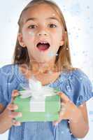 Composite image of excited little girl holding a wrapped gift