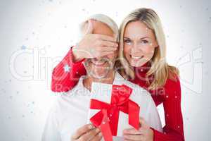Smiling woman covering partners eyes and holding gift