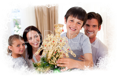 Happy little boy decorating a christmas tree with his family