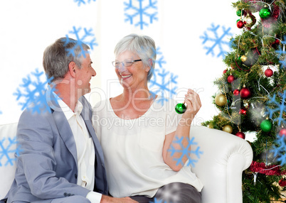 Mature couple sitting on sofa with a christmas tree