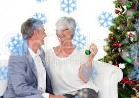 Mature couple sitting on sofa with a christmas tree