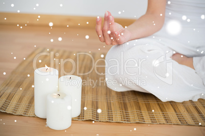 Woman sitting in lotus pose beside white candles