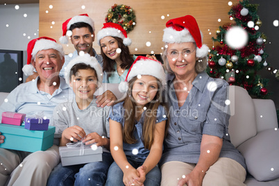 Extended family in christmas hats with gift boxes in living room