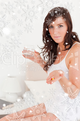 Attractive brunette female taking some pills while sitting