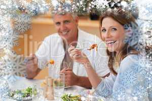 Composite image of laughing couple eating dinner