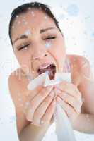 Woman sneezing into a tissue