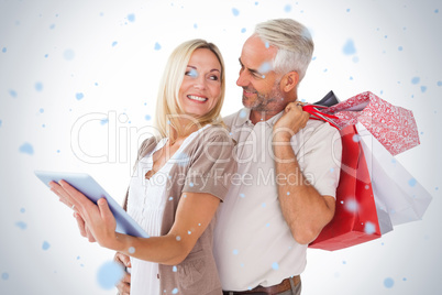 Happy couple holding shopping bags and looking at tablet pc