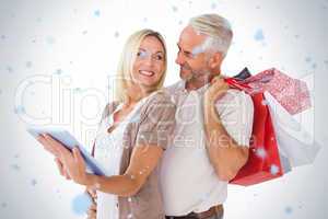 Happy couple holding shopping bags and looking at tablet pc