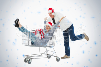 Festive mature couple in winter clothes with trolley and gifts