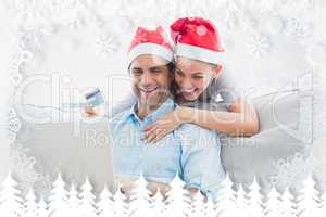 Smiling couple in santa hats shopping online with laptop