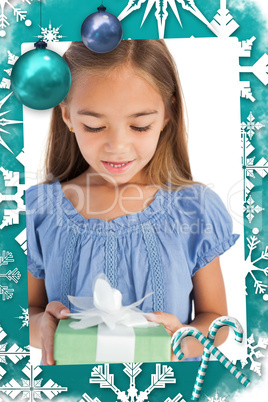 Composite image of cute little girl holding a wrapped gift