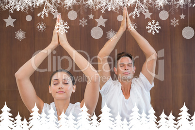 Peaceful couple in white doing yoga together with hands raised