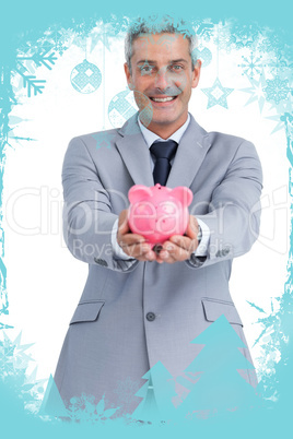 Composite image of joyful businessman holding piggy bank