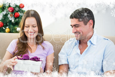 Composite image of woman opening christmas gift