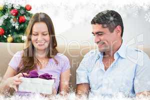 Composite image of woman opening christmas gift