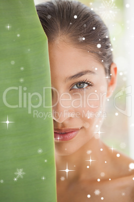 Beautiful brunette smiling at camera behind leaf